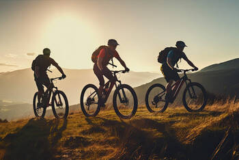 3 Mountainbiker fahren im Sonnenuntergang Berg hoch