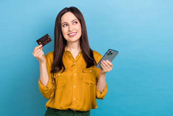 Frau hält Smartphone und Kreditkarte in die Luft