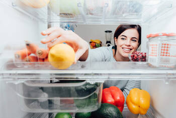 Frau greift in den Kühlschrank
