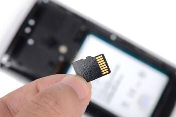 MicroSD wird vor ein Smartphone gehalten