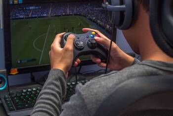 Mann mit Kopfhörern spielt Fifa auf einer Spielkonsole