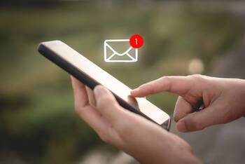 Person bedient Smartphone, über welchem ein Briefsymbol zusehen ist, welches eine neue Nachricht indiziert