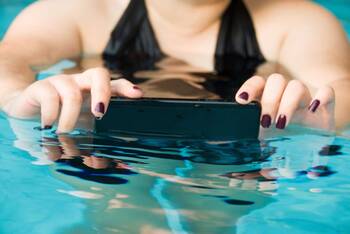 Frau im Wasser macht ein Foto mit ihrem Smartphone im Wasser.