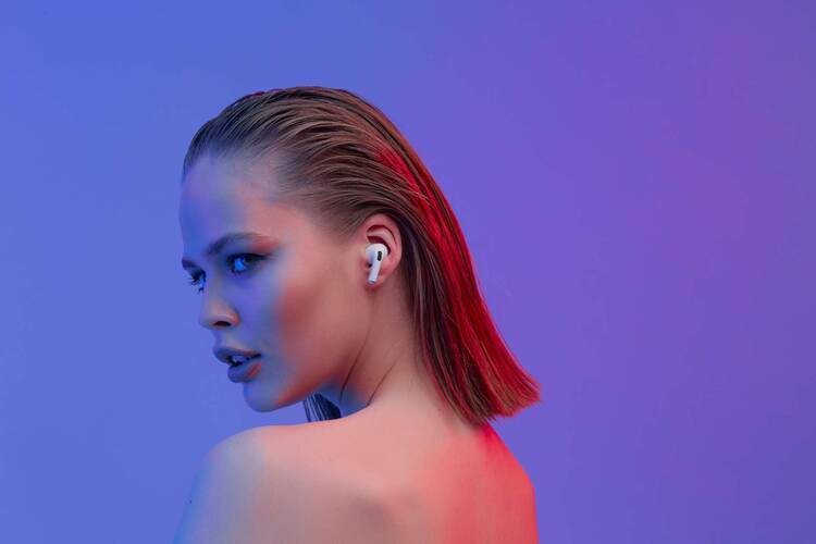 Modern geschminkte Frau vor lila Hintergrund mit AirPod Pro im Ohr