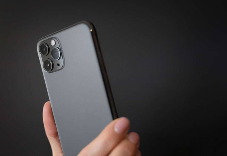 Schwarzes iPhone mit drei Kameras vor schwarzem Hintergrund