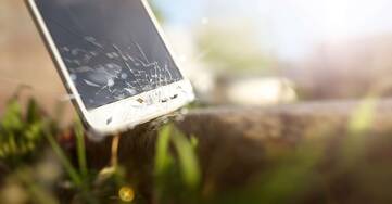 ein Smartphone mit einem beschädigtem Display fällt zu Boden