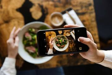 Person fotografiert Essen mit einem Smartphone 