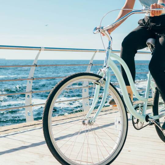 Frau auf Fahrrad in Vintage Optik am Meer