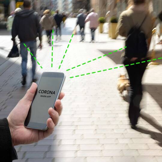 Person mit Handy in der Hand auf Straße, das virtuell Linien zieht zu anderen dort laufenden Menschen