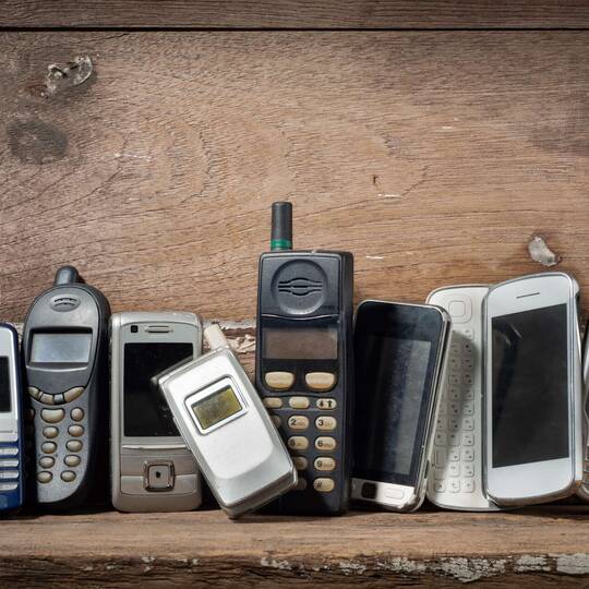 Alte Mobiltelefone an Holzwand gelehnt