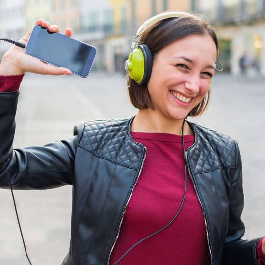 Frau hört Musik mit Overear-Kopfhörern über ihr Smartphone