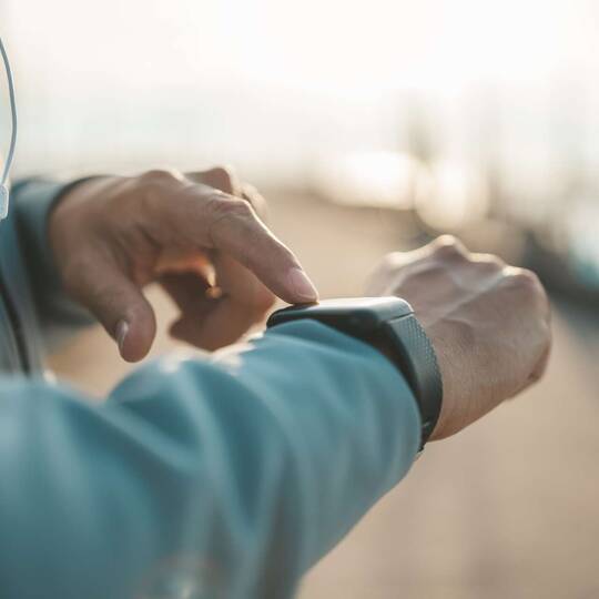 Person Outdoor tippt mit einer Hand auf Smartwatch an anderem Handgelenk