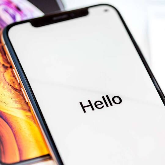 ein iPhone liegt auf dem Tisch und zeigt "Hello" an