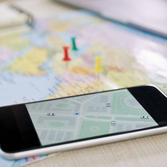 Smartphone mit Landkarte auf dem Bildschirm liegt auf einer Landkarte