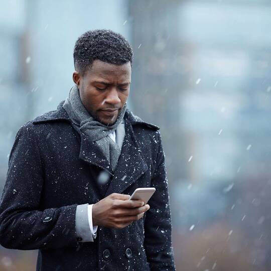 Person mit iPhone im Schneegestöber
