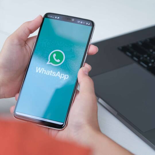 Person hält Smartphone mit geöffneter WhatsApp Anwendung
