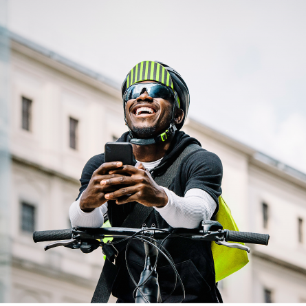 Ein Mann stützt sich auf dem Lenker seines Fahrrads ab und lacht
