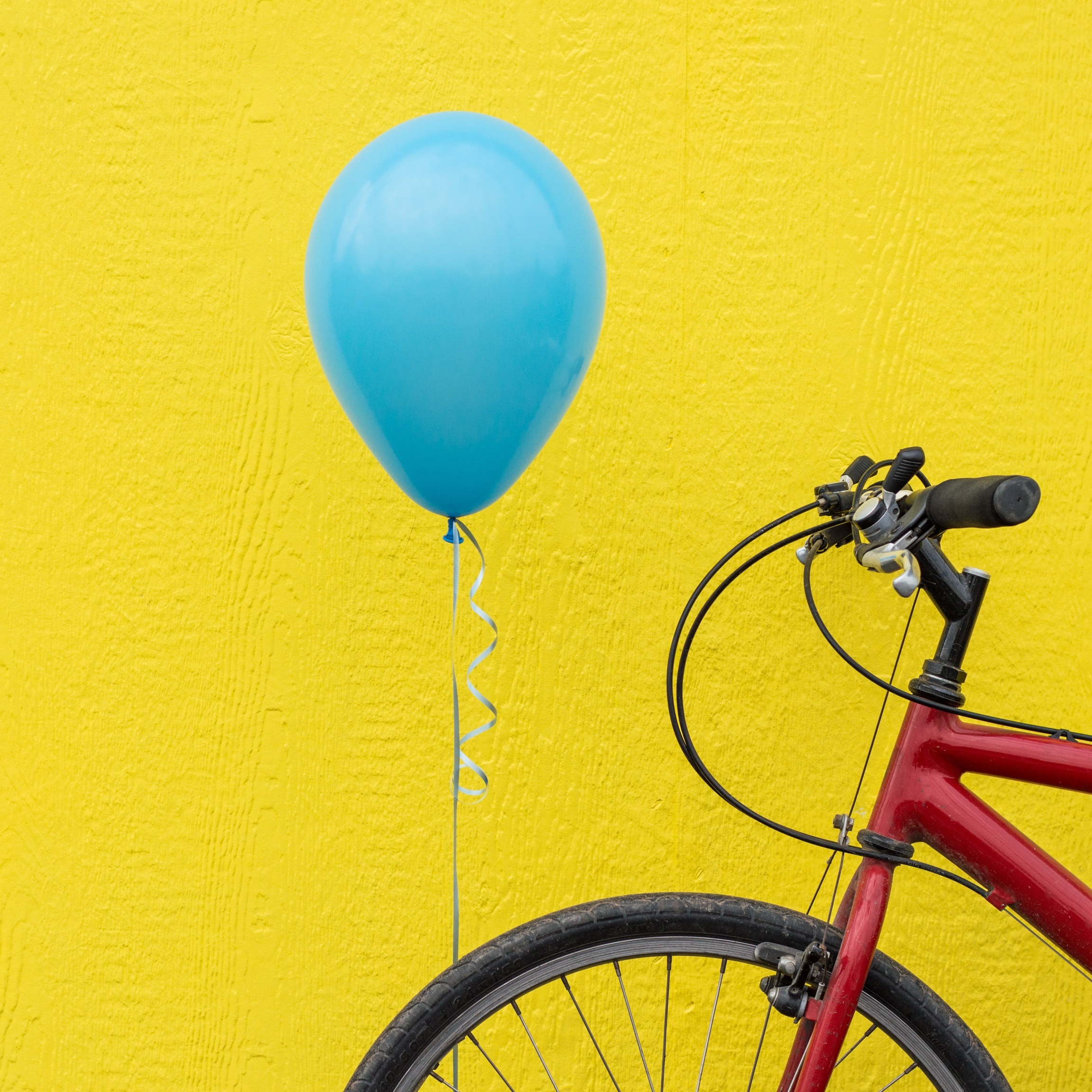 Ein rotes Fahrrad mit einem blauen Ballon am Vorderreifen angebracht.