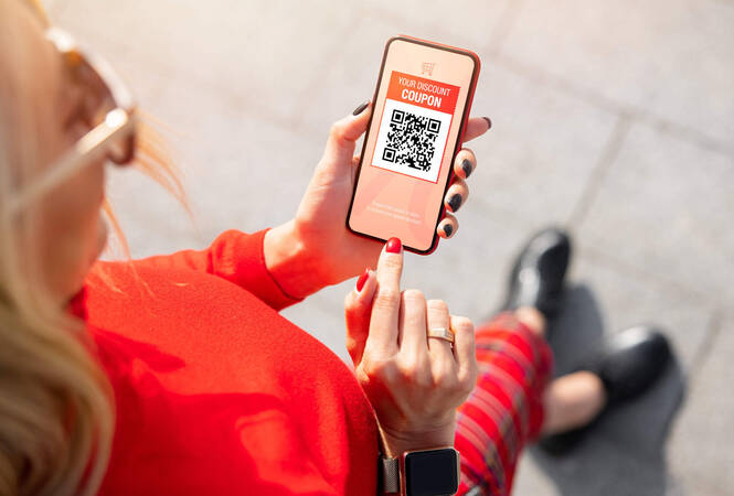 Eine Frau guckt sich auf ihrem Smartphone einen Coupon an.