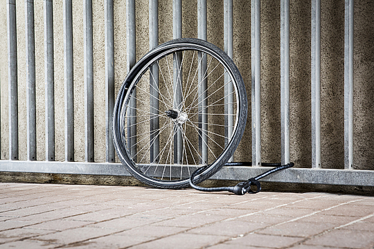 Nur noch ein Rad ist an einem Metallzaun angeschlossen, Rahmen und Rest des Fahrrads sind geklaut