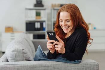 Frau schaut lächelnd auf Smartphone Display