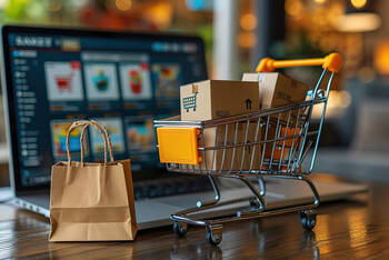 Auf der Tastatur von einem Laptop steht ein Mini-Einkaufswagen.