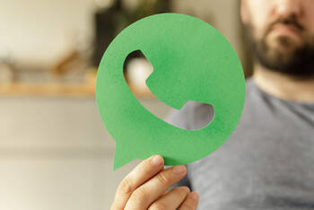 Ein Mann hält ein Icon von einer Messenger-App in der Hand.