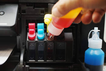 Eine Person füllt die Farbtanks im Drucker auf.