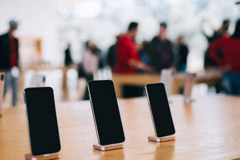 Mehrere iPhones stehen ausgestellt auf einem Tisch.