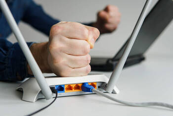 Eine Person haut auf den WLAN-Router.