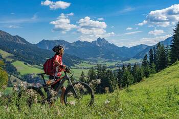 Frau schiebt E-Mountainbike durch die Berge