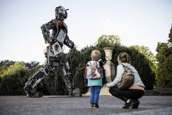 Ein Kind und eine Frau schauen auf eine Skulptur aus Elektroschrott.