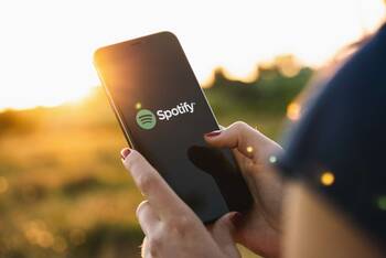 Person hält Smartphone mit Spotify-Logo auf dem Display in der Hand