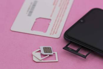 Smartphone mit Dual-SIM-Schiene und SIM-Cards liegt auf rosa Untergrund