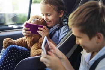 Zwei Kinder spielen im Auto in ihren Handys