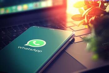 Smartphone mit geöffneter WhatsApp Anwendung liegt auf Laptop