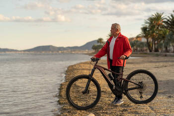 Mann steht mit Mountainnbike am Strand