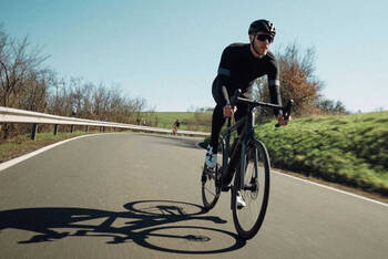 Mann fährt auf Rennrad über Strasse.