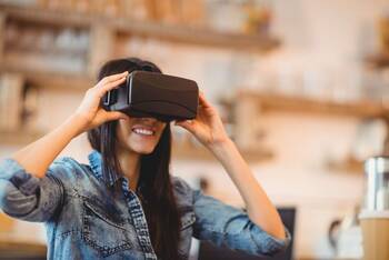 Eine Frau lächelt, während sie sich eine VR-Brille vor den Kopf hält