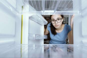 Eine Frau guckt in einen leeren Kühlschrank