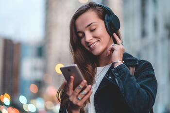 Frau hört mit Smartphone Musik über Kopfhörer
