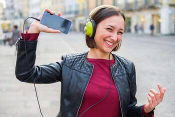 Frau hört Musik mit Overear-Kopfhörern über ihr Smartphone