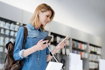 Frau im Elektronikladen mit zwei verschiedenen Smartphones in den Händen
