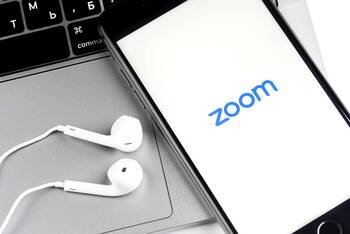 Smartphone liegt auf Laptop mit geöffneter Zoom App
