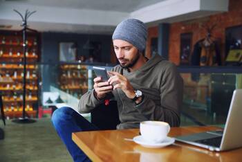 Mann sitzt in einem Cafe und nutzt sein Smartphone
