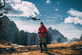 Mann fliegt Drohne in Bergen
