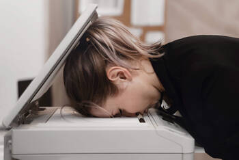 Frau legt Kopf in Drucker und ist verzweifelt