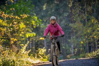 Eine Frau fährt im Wald ihr E-Bike