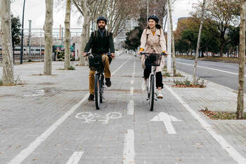 Zwei Personen fahren nebeneinander auf Fahrrädern über einen Radweg.