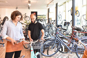 Mann und Frauen stehen vor einem Fahrrad und begutachten es.